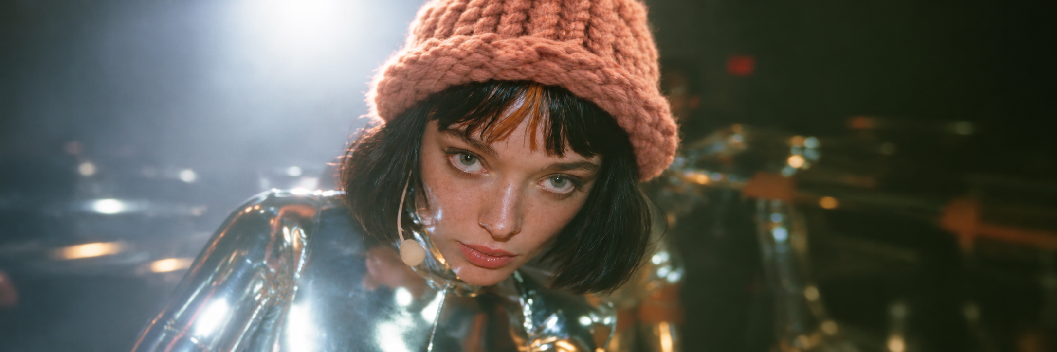 WIFCLAUDIA wearing a peach-pink knitted beanie and a reflective silver outfit